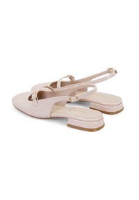 Chaussures slingback en cuir verni beige avec un petit talon carré, présentant un design fendu et des accents de boucle en ton doré. Texture lisse.