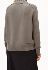 Pull gris en maille avec un col montant, des poignets et un ourlet côtelés. Présente une coupe décontractée et une surface texturée, vu de dos.