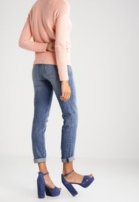 Ljusrosa ribbad tröja, blå manschettjeans och blå mockaplatåskor med öppen tå och ankelrem.