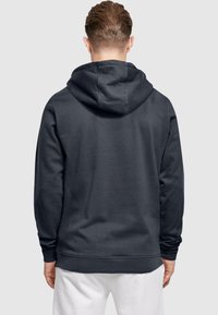 Tmavošedá mikina s kapucňou, dlhými rukávmi, rebrovanými manžetami a spodným lemom, s hladkou textúrou a minimalistickým dizajnom.