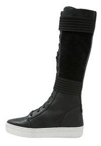 Černé vysoké kozačky s hladkým koženým špičkou a měkkým, strukturovaným semišovým svrškem. Obsahují vertikální pruhy a bílou gumovou podrážku.