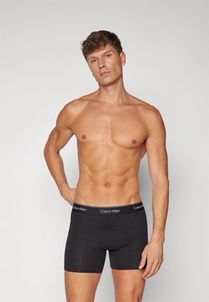 Boxer-briefs noirs en coton avec une coupe ajustée, ceinture élastique ornée du logo blanc "Calvin Klein", design uni et longueur mi-cuisse.