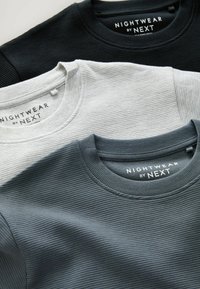 Kolme pitkähihaista crew neck -paitaa mustasta, harmaasta ja tummanharmaasta ribbikankaasta. Jokaisessa on etiketti, jossa lukee "NIGHTWEAR by NEXT."