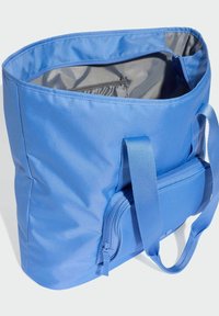 Blue nylon tote bag with a smooth texture, large main compartment, and a smaller zippered pocket on the front. Sturdy fabric straps.
