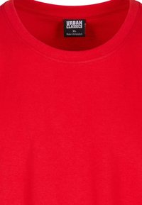 Camiseta de algodón roja con cuello redondo, que presenta una etiqueta con la marca "URBAN CLASSICS" y tamaño "XL". Textura suave y color uniforme.