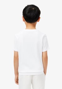 White cotton t-shirt with short sleeves, round neckline, and a straight hem. Simple design, smooth texture, and no visible graphics.
