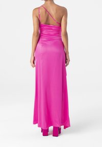 Robe longue rose avec un corsage ajusté et une jupe fluide. Elle possède des bretelles fines ajustables et une texture soyeuse, avec une légère traîne à l'arrière.