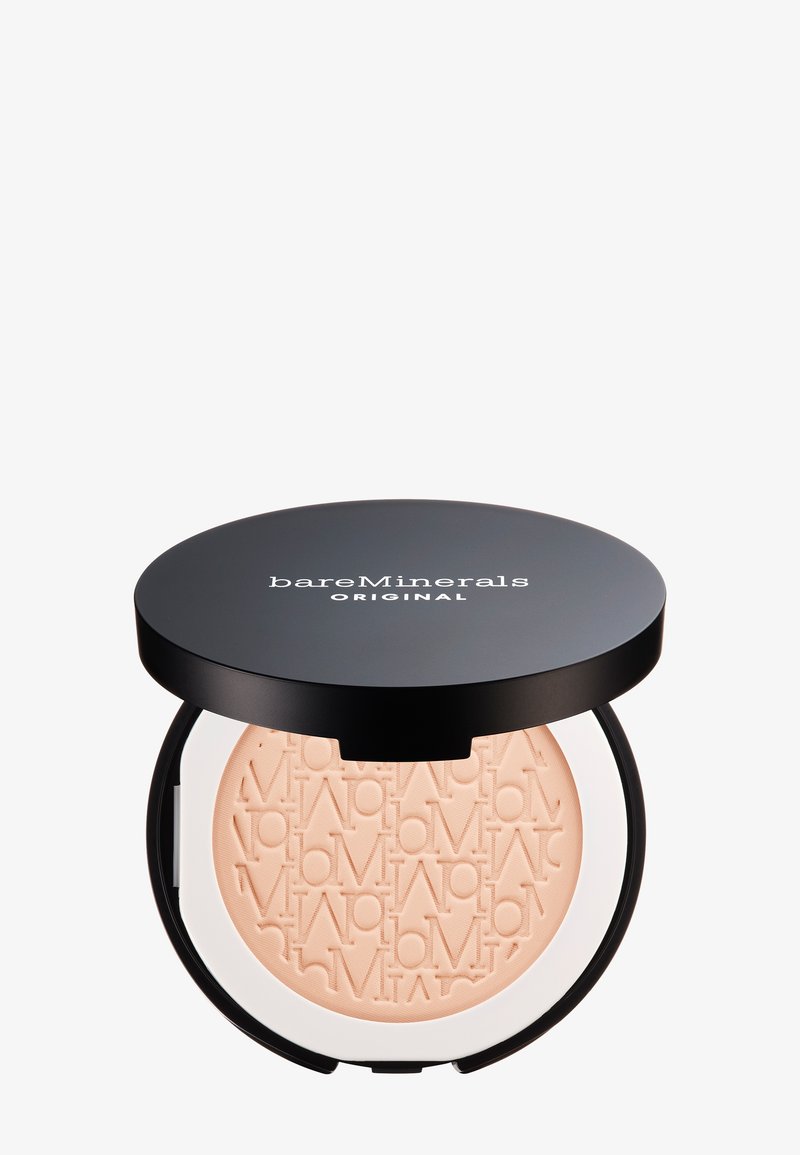 Poudre translucide dans un compact rond noir avec une base transparente. La poudre a une texture fine et est embossée d'un motif de logo répété.