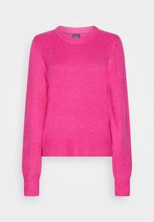 Jasnoróżowy sweter z długimi rękawami i okrągłym dekoltem, z prążkowanymi mankietami i dołem, wykonany z miękkiej dzianiny, na jednolitym tle.