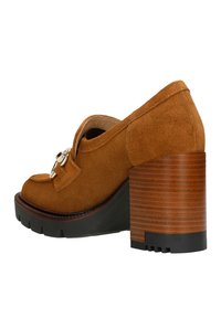 Brown suede heeled shoe with a rounded toe, decorative buckle detail, and a chunky, wood-textured heel. Textured rubber sole for grip.