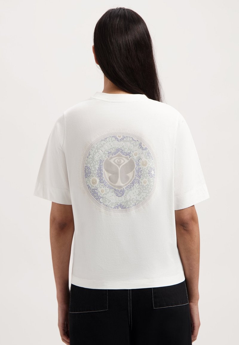 Witte t-shirt met korte mouwen en een ronde grafiek op de achterkant met een logo en intrikate florale patronen in pastelkleuren.