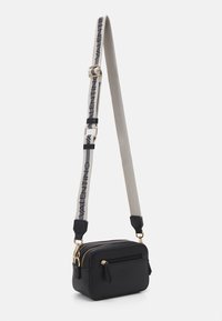 Bolso cruzado de cuero negro con compartimentos dobles con cremallera y una correa de hombro gris de marca que presenta herrajes dorados y acentos negros.