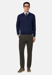 Marineblauwe pullover, katoenmix, met een kraag en knoopsluiting. Grijze corduroy broek en olijfgroene sneakers met textuurdetails.