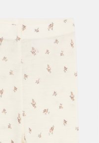 Leggings en coton de couleur crème douce, ornés d'un délicat motif floral dans des tons rose et marron doux, avec une taille élastique.