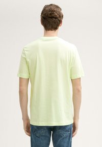 Lys gul t-shirt med korte ærmer og rund halsudskæring, lavet af blødt stof, med et ensfarvet design og lige kant.