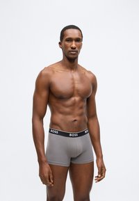 Šedé boxerky s černým pasem s logem "BOSS". Hladká látka s přiléhavým střihem a rovnou linií.
