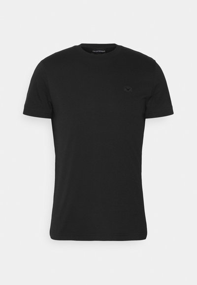 Melnas īsām piedurknēm T-krekls, kas izgatavots no kokvilnas, ar apaļu apkakli un mazu tumšu logotipu uz krūts, ar gludu tekstūru.