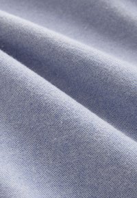 Tessuto azzurro chiaro con una fine trama strutturata, che mostra pieghe drappeggiate che evidenziano la sua morbidezza e la leggera lucentezza. Adatto per varie applicazioni tessili.