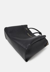 Schwarze Leder-Tote mit strukturiertem Finish, abgerundetem oberen Ende, goldenen Hardware-Details und doppelten Griffen. Minimalistisches Design.