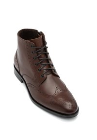 Stivale alla caviglia in pelle marrone con design brogue, caratterizzato da una superficie liscia, dettagli perforati e lacci neri. Punta strutturata e suola resistente.
