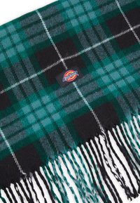 Grøn og sort ternet tørklæde med frynsekanter og et Dickies-logo patch; lavet af blødt, tekstureret stof.