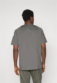 Kortærmet, grå T-shirt med rund halsudskæring, der har raglanærmer og teksturerede detaljer på skuldrene. Blødt, blandet bomuldsstof.
