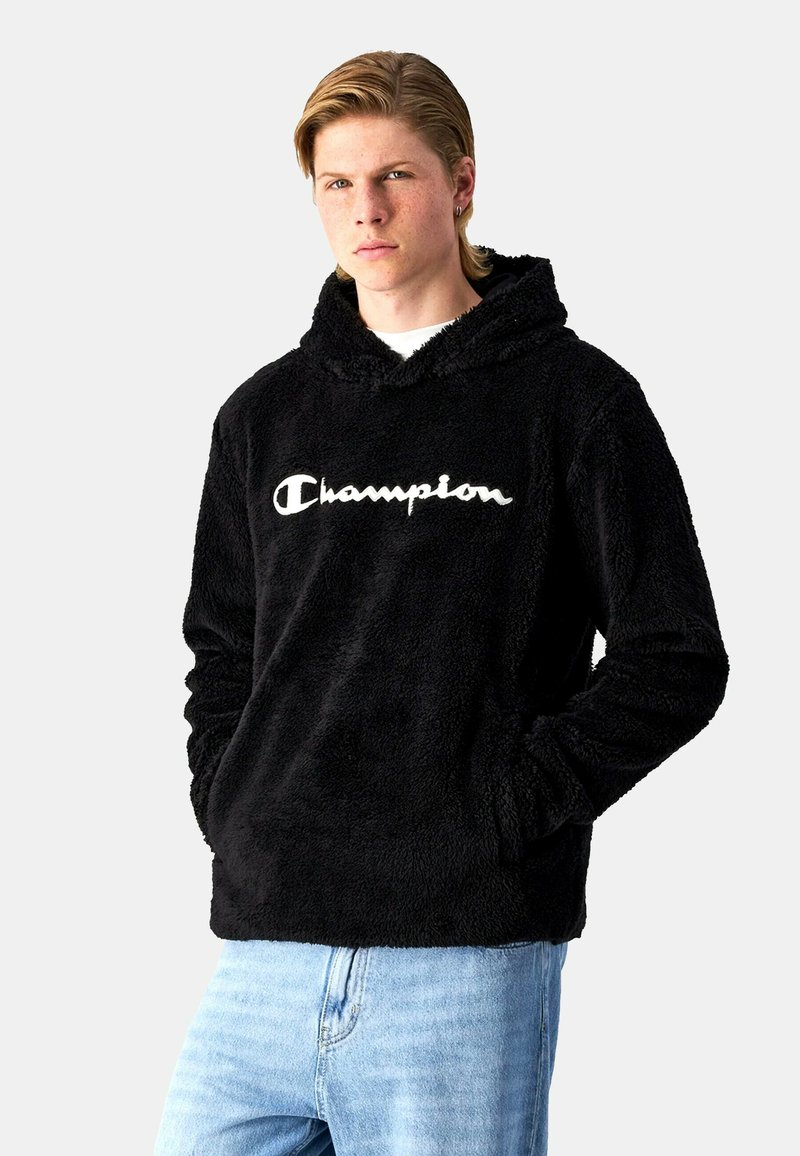 Sudadera de forro polar negra con mangas largas, bolsillos frontales y capucha con cordón. Presenta el logo "Champion" bordado en blanco en el pecho.