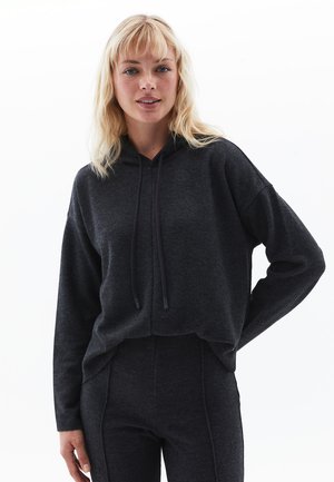 Sweat-shirt à capuche noir en tissu doux et texturé, avec des manches longues, des cordons de serrage réglables et une coupe décontractée.