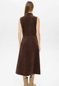 Rjava brezrokavna obleka iz teksturirane tkanine, s po višini ovratnikom in razširjenim krilom, z vpražnimi žepi in ohlapnim krojem.