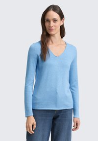 Helleblaue Langarmpullover mit V-Ausschnitt, aus weichem Strickstoff gefertigt. Der Saum ist gerade und ergänzt lässige Denimunterteile.