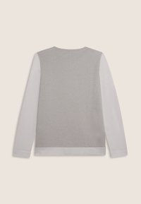 Maglietta a maniche lunghe con maniche grigie chiare e pannello posteriore argentato brillante, mostrata dal retro su uno sfondo beige.