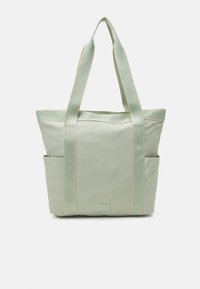 Sac fourre-tout vert avec deux poches latérales, des sangles robustes et une texture lisse avec des coutures claires contrastantes. Design compact et pratique.