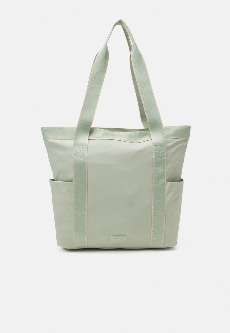 Sac fourre-tout vert avec deux poches latérales, des sangles robustes et une texture lisse avec des coutures claires contrastantes. Design compact et pratique.