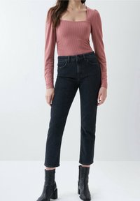 Rosa ribbad långärmad bodysuit med fyrkantig urringning, kombinerad med högmidjade mörk denimjeans och svarta ankelstövlar.