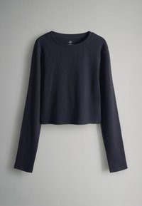 Tums zila, īsā džemperī ar garām piedurknēm, izgatavots no ribota auduma, ar apaļu dekoltē un brīvu piegriezumu, ar minimālu vīļu skaitu un bez redzamām logotipiem.