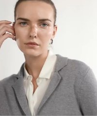 Szary wełniany kardigan z wykładanym kołnierzem, noszony na białej koszuli z kołnierzykiem. Design jest dopasowany, z subtelną teksturą i minimalistycznymi akcentami.