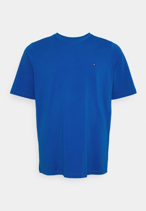 T-shirt bleu uni à manches courtes et col rond avec un petit logo rectangulaire rouge, blanc et bleu sur la poitrine gauche.