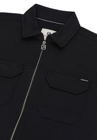Chaqueta negra con cierre frontal, cuello y dos bolsillos con solapa. Fabricada en un tejido suave con detalles de costura y una etiqueta de marca en el bolsillo.