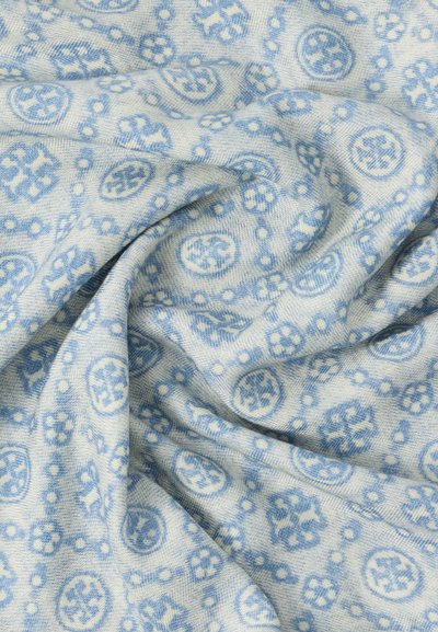 Tissu doux avec des motifs géométriques et floraux bleu clair sur un fond bleu pâle, présenté avec des plis délicats.