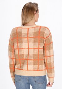 Beige gebreide trui met een oranje en bruine ruitpatroon, geribbelde zoom en ronde halslijn. Zachte textuur en ontspannen pasvorm.