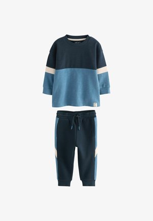 Sweatshirt og joggersæt. Sweatshirten har paneler i mørkeblå og lyseblå. Joggerne er mørkeblå med lyseblå accenter og elastisk talje.