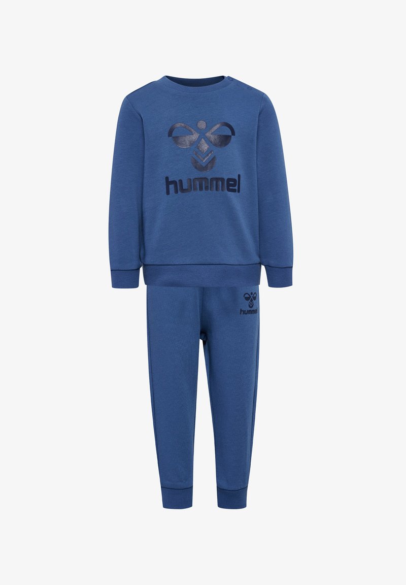 Zestaw niebieskiej bluzy i spodni wykonany z miękkiego materiału. Bluza ma logo i okrągły dekolt. Spodnie mają dopasowany krój i ściągacze na końcach nogawek.