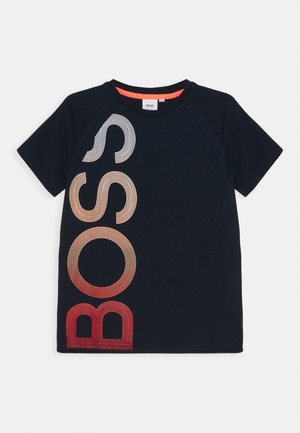 Granatowy t-shirt z krótkim rękawem z napisem „BOSS” w dużych, pionowo ułożonych literach przechodzących od białego do czerwonego po lewej stronie.