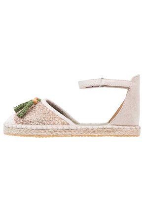 Sandalo espadrille aperto con tomaia intrecciata in oro e beige, adornato con un pon-pon verde e una perla di legno, dotato di chiusura con cinturino.