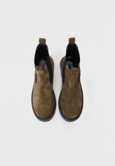 Καφέ σουέντ μποτάκια Chelsea με μαύρο ελαστικό πάνελ, στρογγυλερή μύτη και μαύρη ελαστική σόλα. Διαθέτουν διπλές θηλιές για εύκολη φόρεση.