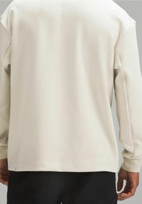 Helle beige Pullover-Sweatshirt mit langen Ärmeln, gerippten Bündchen und entspannter Passform. Weicher Stoff, minimale Nähte im Rückenbereich.