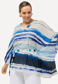 Blusa fluida con scollatura a V e maniche ampie, caratterizzata da un motivo a righe blu e bianche. Il materiale sembra leggero e trasparente.