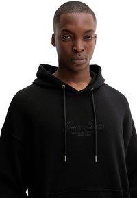 Felpa nera con cappuccio e vestibilità comoda, con logo ricamato sul davanti, coulisse piatte e tasca a marsupio.