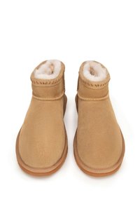 Pair of light brown suede ankle boots with soft white fur lining and stitched detailing, displayed on a white background.