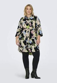 Πολύχρωμη μπλούζα με άνετη γραμμή, διακοσμημένη με floral μοτίβο σε πράσινο, μαύρο, ροζ και μπλε, ζωνάκι στη μέση, συνδυασμένη με μαύρα κολάν και μποτάκια μέχρι τον αστράγαλο.